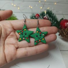 two green christmas tree shaped earrings on a person's hand