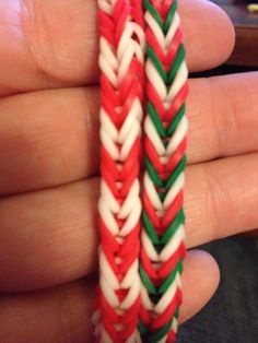 someone is holding two red, white and green braided bracelets