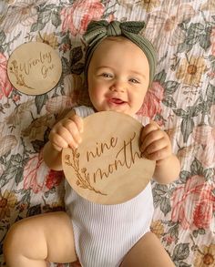 a baby holding up a wooden sign that says mine month