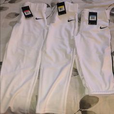 two white nike pants laying on top of a bed