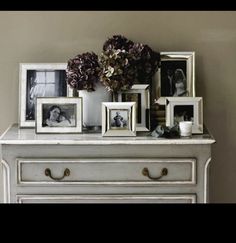 an old dresser with pictures and flowers on it