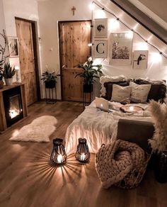 a bedroom with wooden floors and lights on the wall above the bed is lit by candles