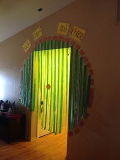 a room with yellow and green curtains on the wall, and a door decorated with ribbons