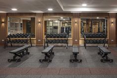 an empty gym with benches and dumbbells