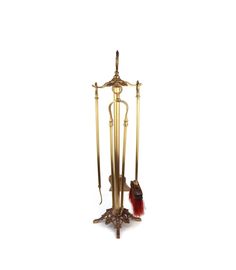 an old fashioned brass wind chime with two red feathers on it's stand