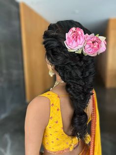 a woman with flowers in her hair is wearing a yellow sari and has pink flowers in her hair