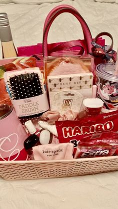 a pink purse filled with lots of beauty and personal care items sitting on a bed