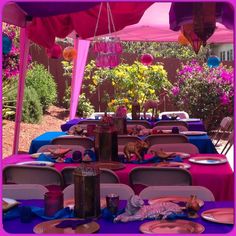 an outdoor table set up with plates and napkins