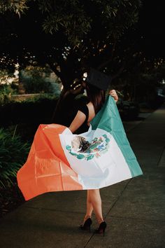 a woman holding an irish flag on the sidewalk