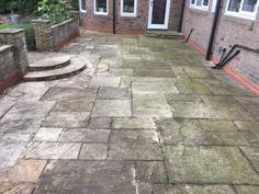 a stone patio with steps leading up to the back door and side windows on either side