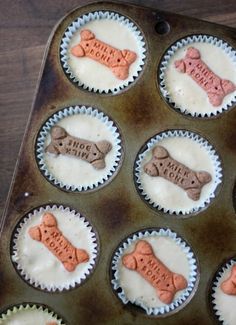 cupcakes decorated with dog bone shaped frosting in a muffin tin on top of a wooden table