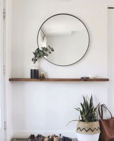 a round mirror hanging on the wall above a potted plant