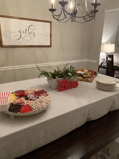 a table topped with plates and bowls filled with food next to a chandelier