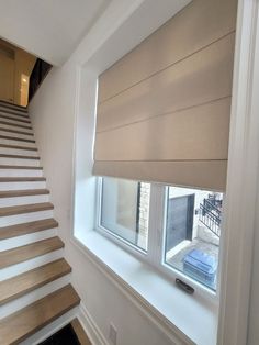 a window with blinds on the side of it and some stairs in front of it