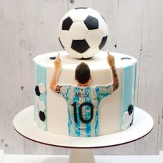 a cake with a soccer ball on top and a man holding his hands up in the air