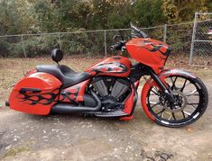 a red and black motorcycle parked in front of a fence