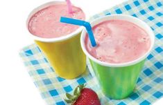 two cups with strawberries on a blue and white checkered table cloth