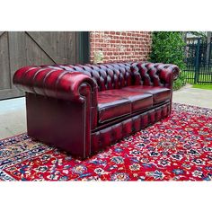 a red leather couch sitting on top of a rug in front of a brick building