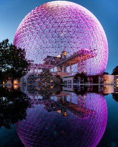 a large purple ball sitting on top of a body of water next to a building