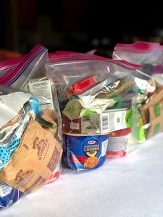 several bags of food sitting on top of a white table covered in plastic wrappers