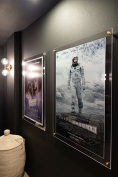 two movie posters hang on the wall next to a round basket in front of them