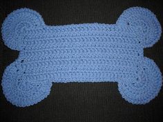 a crocheted blue teddy bear laying on top of a black surface