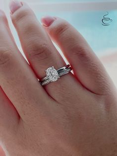 a woman's hand with a diamond ring on top of her finger and the other hand is holding an engagement ring