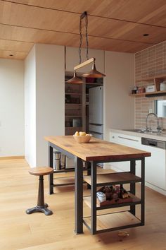 a kitchen with a wooden table and two stools next to an island in the middle