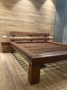 a wooden bed frame sitting on top of a hard wood floor next to a wall