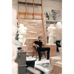 a man sitting on a chair in a room with lots of furniture and art work