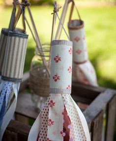 three vases with ribbons tied to them sitting on a wooden table in the grass