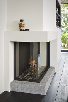 a fireplace in a room with white walls and wood flooring on the wooden floors