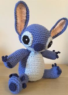 a crocheted blue stuffed animal sitting on top of a wooden table