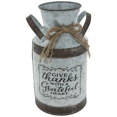 a metal vase with a saying on the front and brown ribbon around it's neck