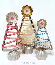 three christmas trees made out of metal with pearls and beads on them, each decorated in different colors