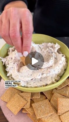 a person dipping some crackers into a bowl of dip