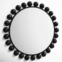 a round mirror with black balls around it