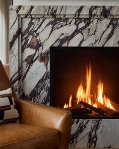 a living room with a chair and fire place in front of a marbled fireplace