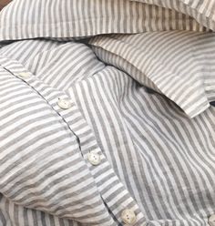 a pile of pillows sitting on top of a wooden table next to a potted plant