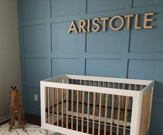 a baby crib in front of a blue wall with the name aristote on it