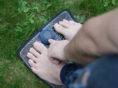 a person is holding an object in their hand while sitting on the ground with it's foot