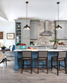 a large kitchen with blue cabinets and an island in the middle is decorated with hanging lights