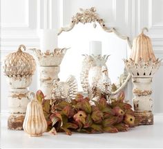 an assortment of vases and candle holders on a white table with flowers in the foreground