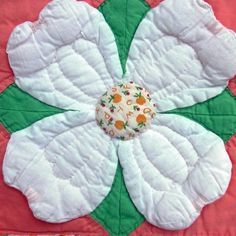 a white flower on a pink and green quilt