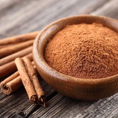 cinnamon sticks and powder in a wooden bowl