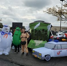 two people standing next to some inflatable cars and ghostbuss on the street