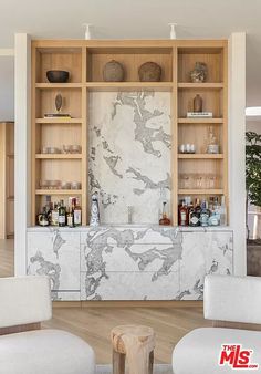 a living room filled with white furniture and wooden shelves