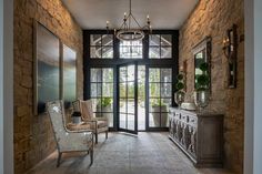 an elegant entry way with stone walls and glass doors, chandelier and chairs