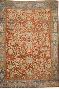 an orange, blue and beige rug with floral designs on the bottom half of it