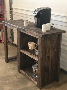 a wooden table with two cups on it and a coffee maker sitting on top of it